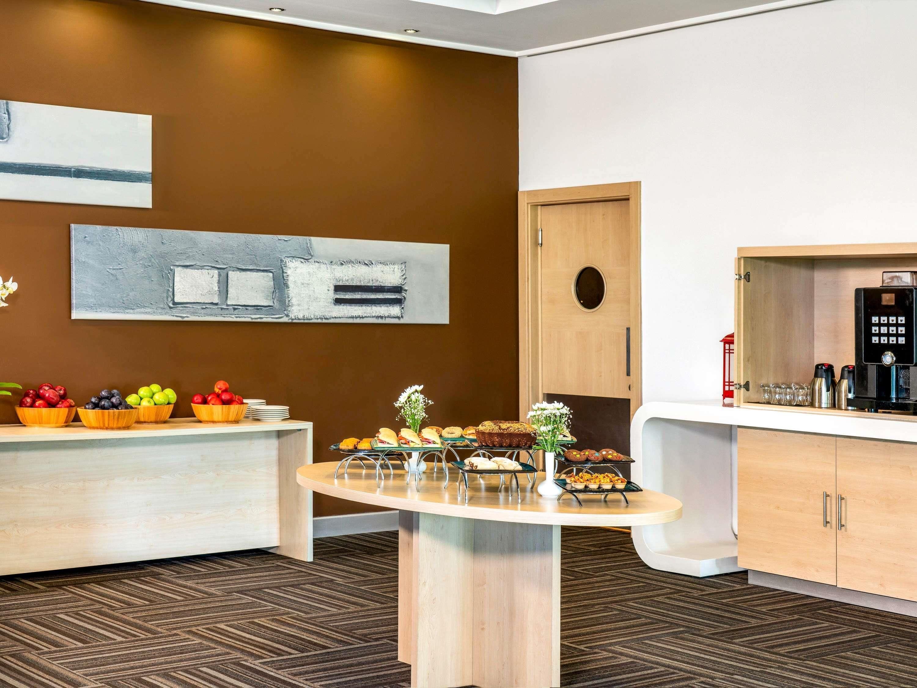 A hotel room with a breakfast bar, a coffee machine, and a wooden cabinet.