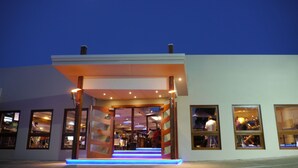 A modern building with a covered entrance, multiple windows, and a staircase leading inside. - Hoey Moey Backpackers - Hostel (Coffs Harbour)