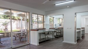 A modern kitchen with a large island, sliding glass doors leading to a patio, and a view of the backyard. - Hoey Moey Backpackers - Hostel (Coffs Harbour)