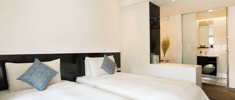 Una habitación de hotel moderna con dos camas, un espejo grande y un área de baño separada.