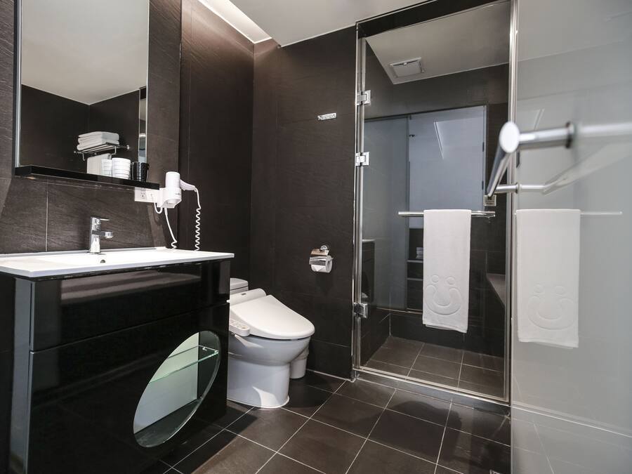 A modern bathroom with a glass-enclosed shower, a toilet, and a vanity with a mirror and towel rack.