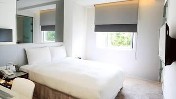 Quarto de hotel moderno com uma cama grande, uma escrivaninha com telefone, um espelho, uma janela com vista e uma televisão.