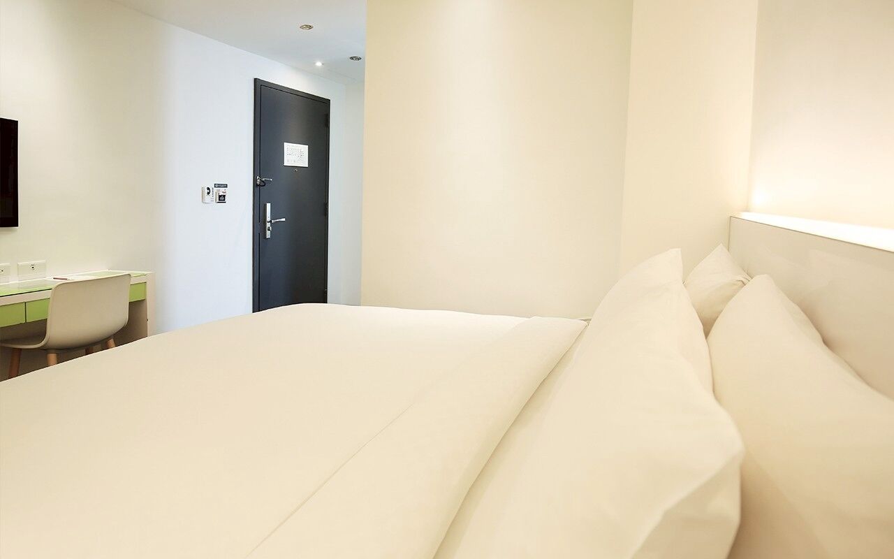 A hotel room with a bed, a desk, and a door.