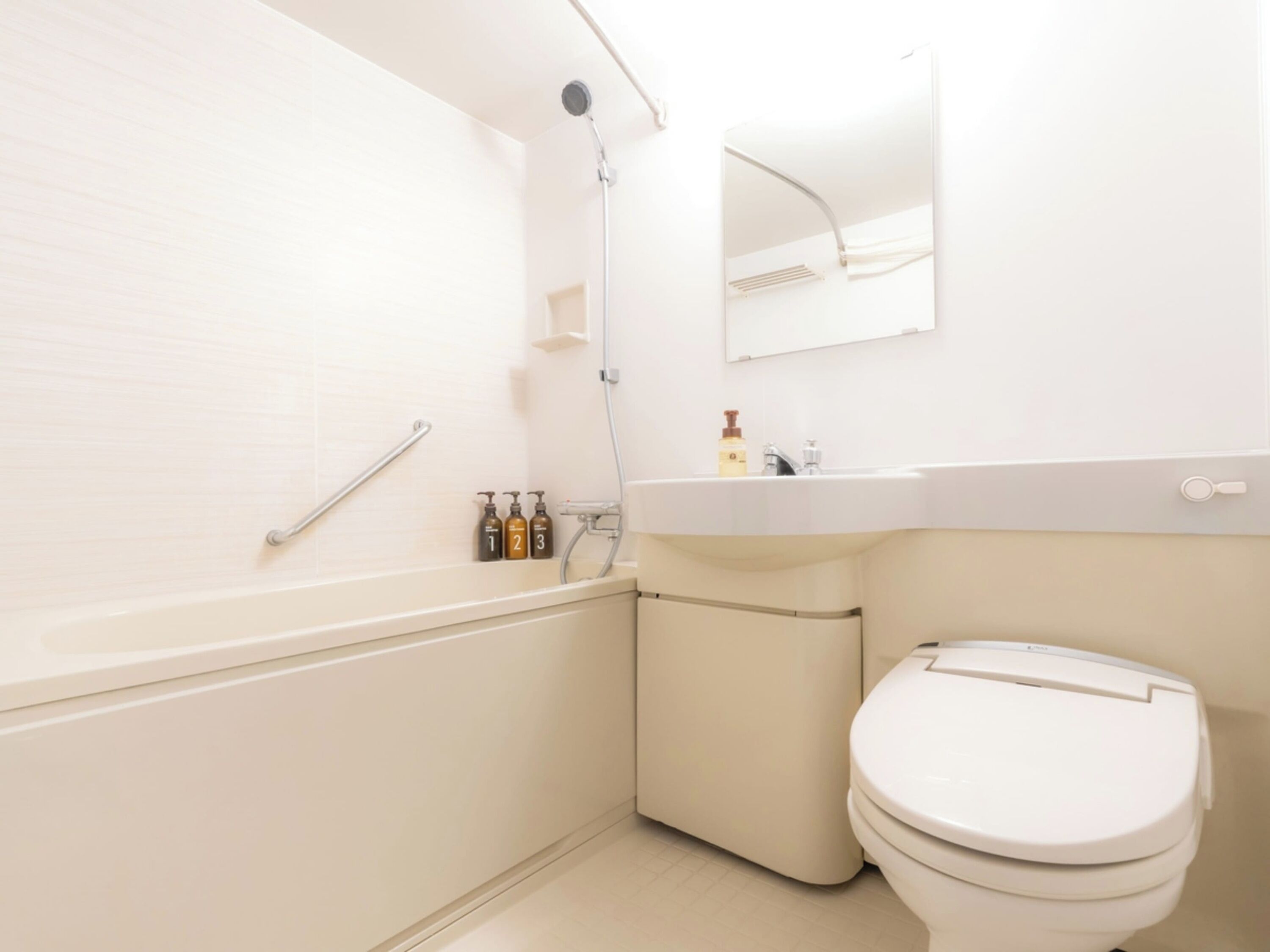 Un baño con bañera, inodoro y lavamanos con dispensadores de jabón.