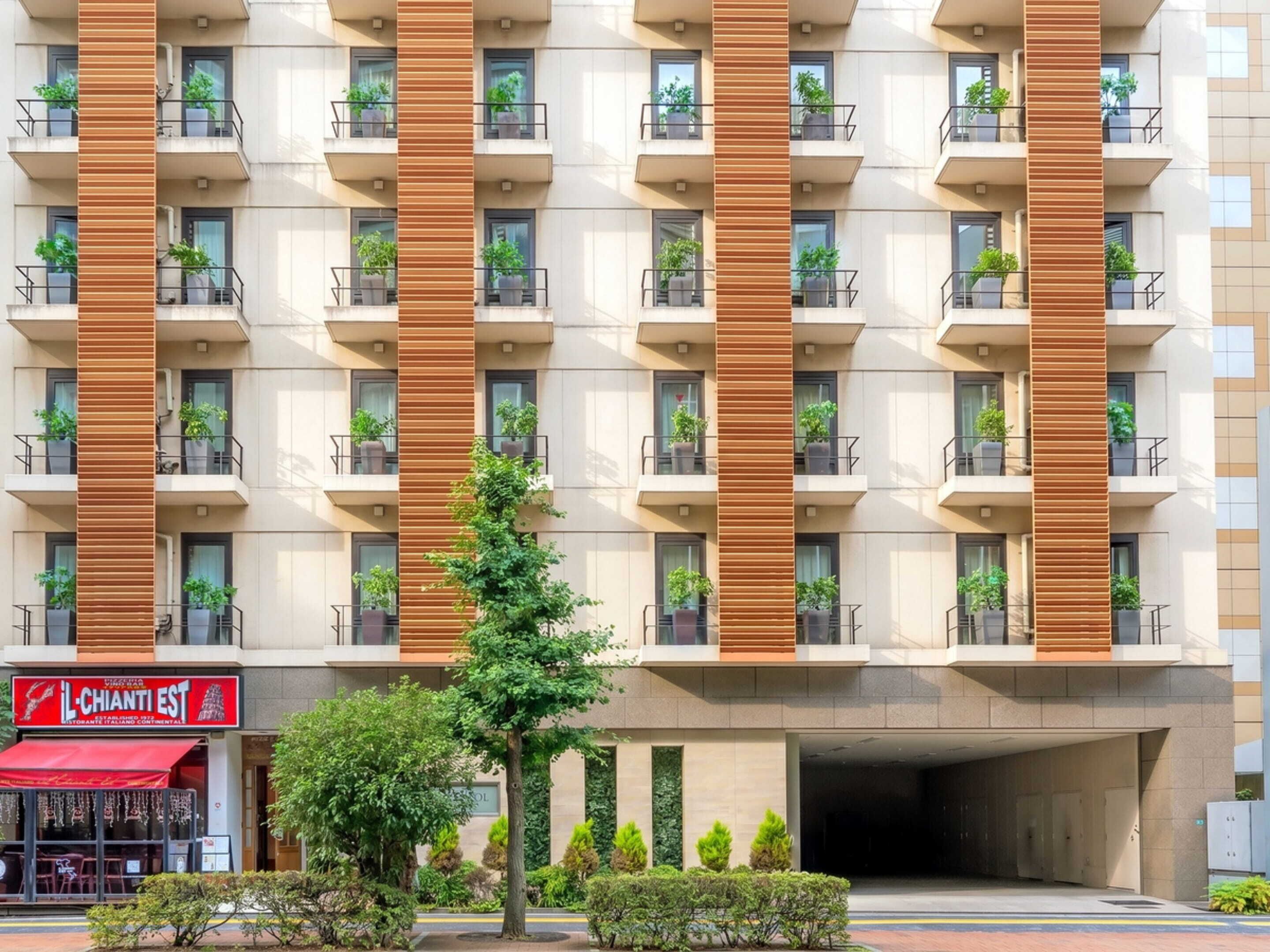 A multi-story hotel with balconies, a restaurant on the ground floor, and a covered entrance.
