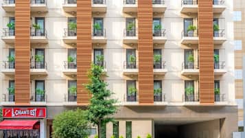 A multi-story hotel with balconies, a restaurant on the ground floor, and a covered entrance.