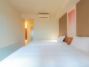 A hotel room with a large bed, a wall-mounted air conditioner, and a door leading to another room. - Hotel Resol Ikebukuro (Tokyo)