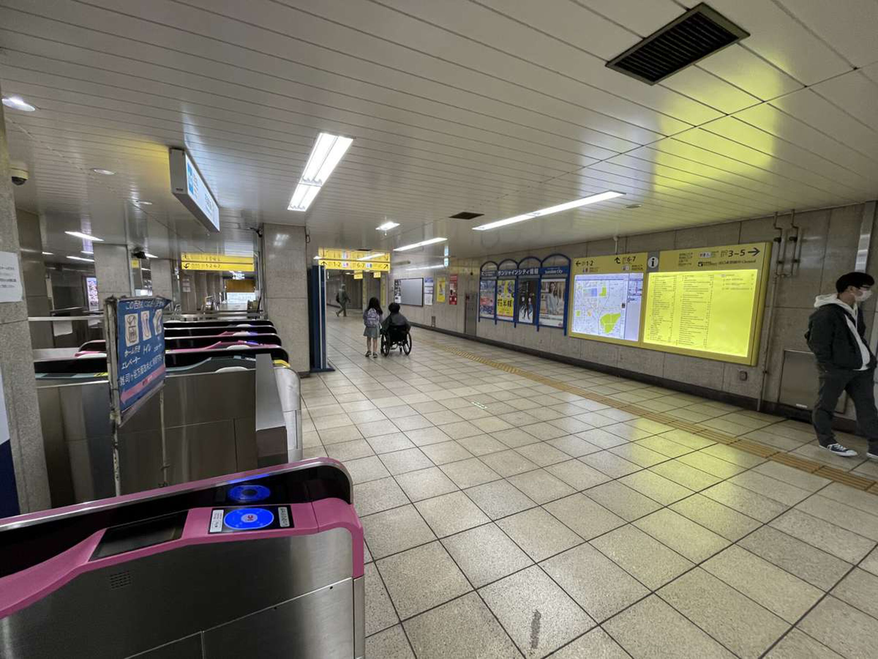 A subway station with ticket barriers, directional signs, and information boards.
