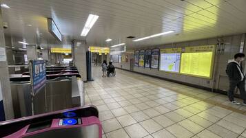 A subway station with ticket barriers, directional signs, and information boards.