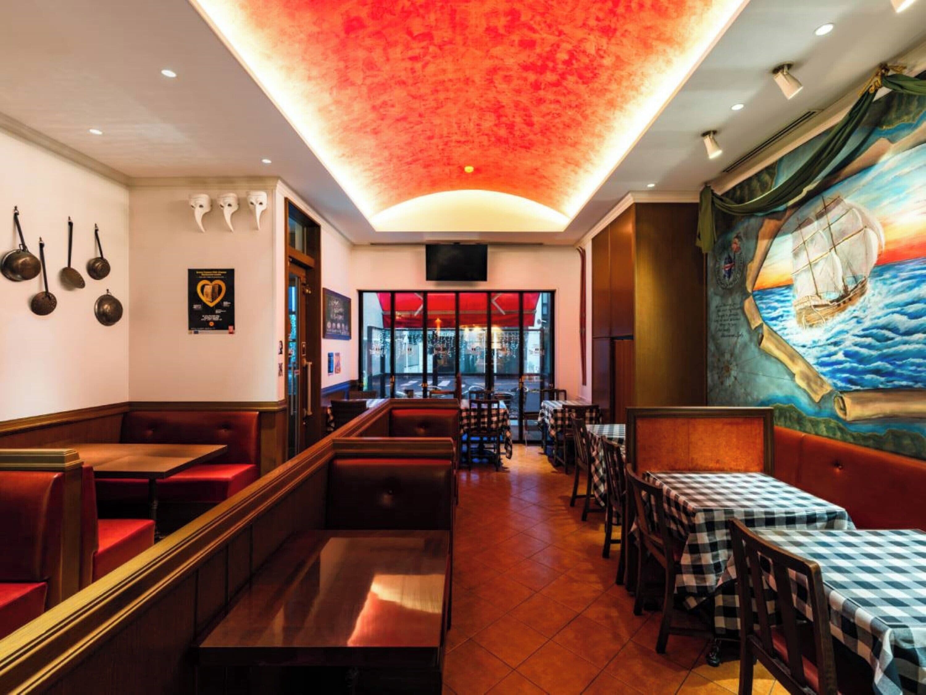 A restaurant interior with booths, tables, and a mural of a sailing ship.