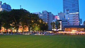 A hotel with a modern design, surrounded by a grassy area and trees. - Hotel Resol Ikebukuro (Tokyo)