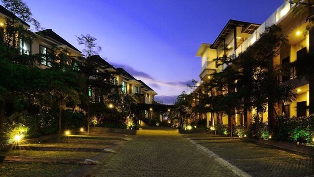 A hotel corridor with multiple floors, illuminated by warm lighting, and surrounded by lush greenery. - Parkside DenBukit Residence & Suite Jimbaran (Jimbaran)
