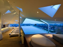 Un interno moderno con un pontile in legno, posti a sedere bianchi e vista su una zona residenziale.
