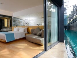 Quarto de hotel moderno com cama grande, sofá, piscina com cobertura de vidro e design de parede geométrico.