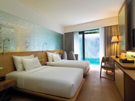 Ein Hotelzimmer mit zwei Betten, einem Schreibtisch, einem Stuhl, einem Fernseher und Blick auf einen Pool.