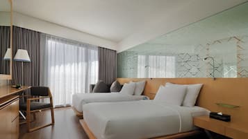 Una habitación de hotel moderna con dos camas, un escritorio, una silla y un ventanal con cortinas.