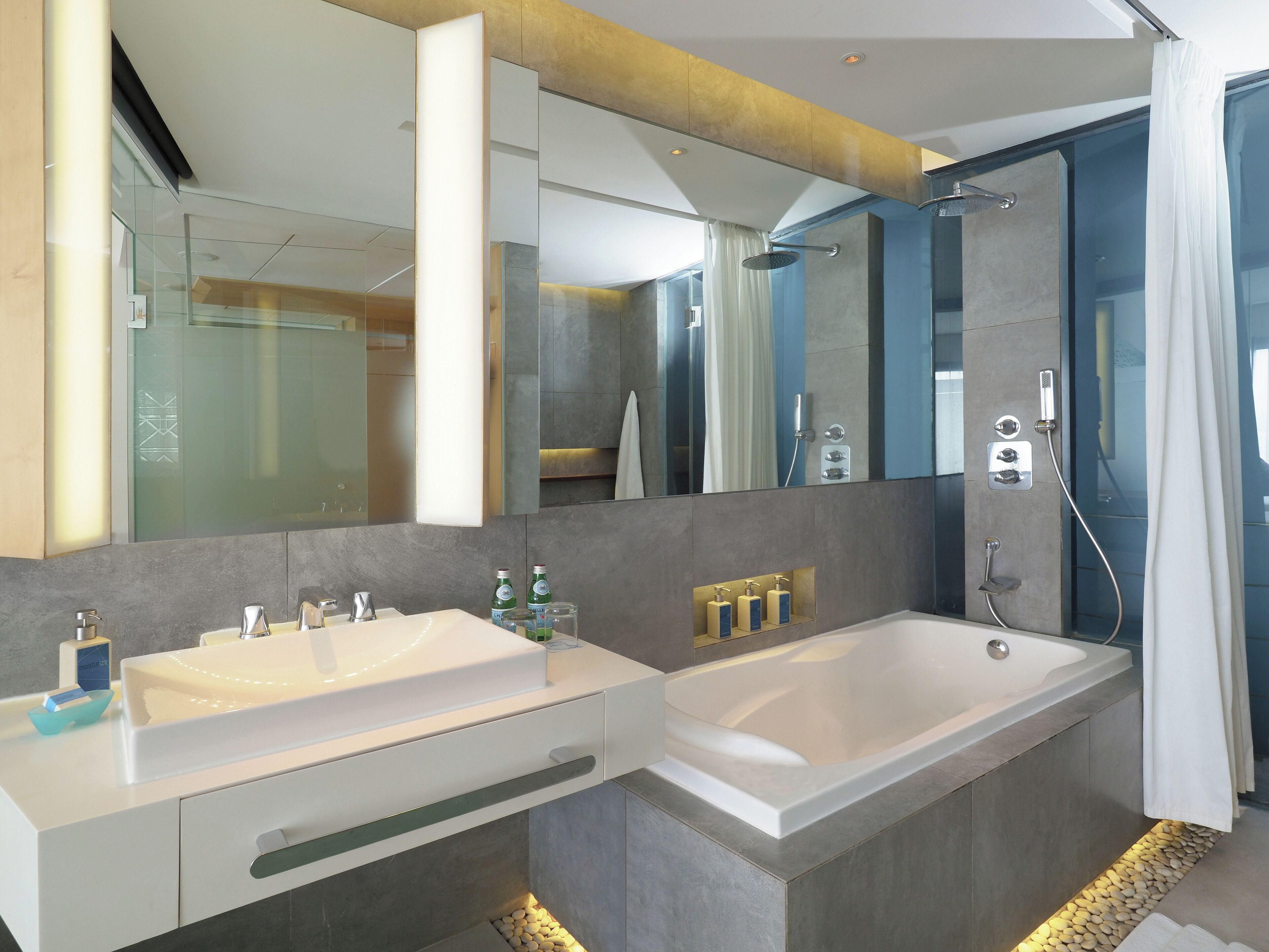 A modern bathroom with dual sinks, a large bathtub, and a walk-in shower.