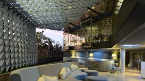 A modern lobby with a geometric ceiling, a sectional sofa, and a staircase leading to an upper level. - IZE Seminyak by LifestyleRetreats (Seminyak)