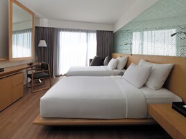 Una habitación de hotel con una cama grande, un escritorio, una silla, una lámpara y un espejo amplio.