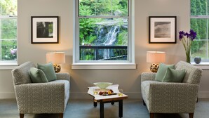 A room with two patterned armchairs, a small table with a bowl and fruits, and framed pictures on the walls. - Ledges Hotel (Hawley)