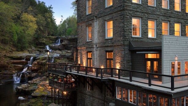 A stone building with multiple windows and a balcony overlooking a waterfall. - Ledges Hotel (Hawley)