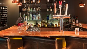 A bar area with a wooden counter, copper pendant lights, and a variety of liquor bottles on shelves. - Ledges Hotel (Hawley)