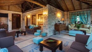 A cozy living room with stone walls, wooden beams, and comfortable seating. - Achtis Boutique Hotel (Kassandra)