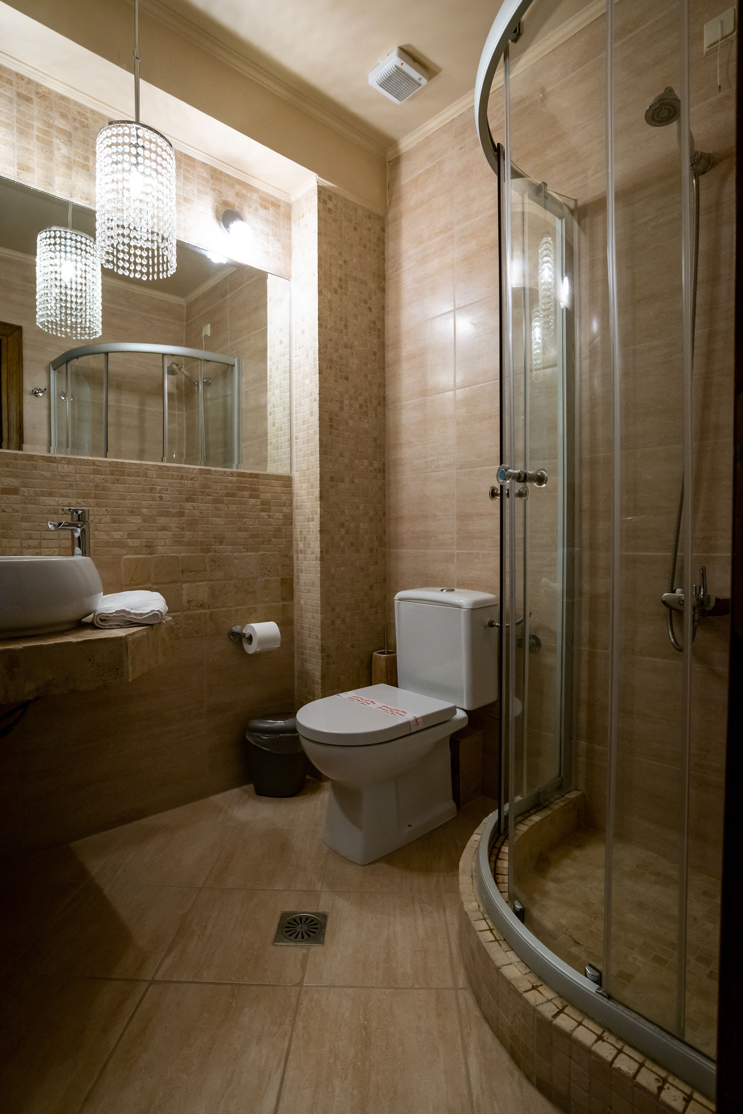 Un baño moderno con cabina de ducha de vidrio, un lavabo con espejo y un inodoro.