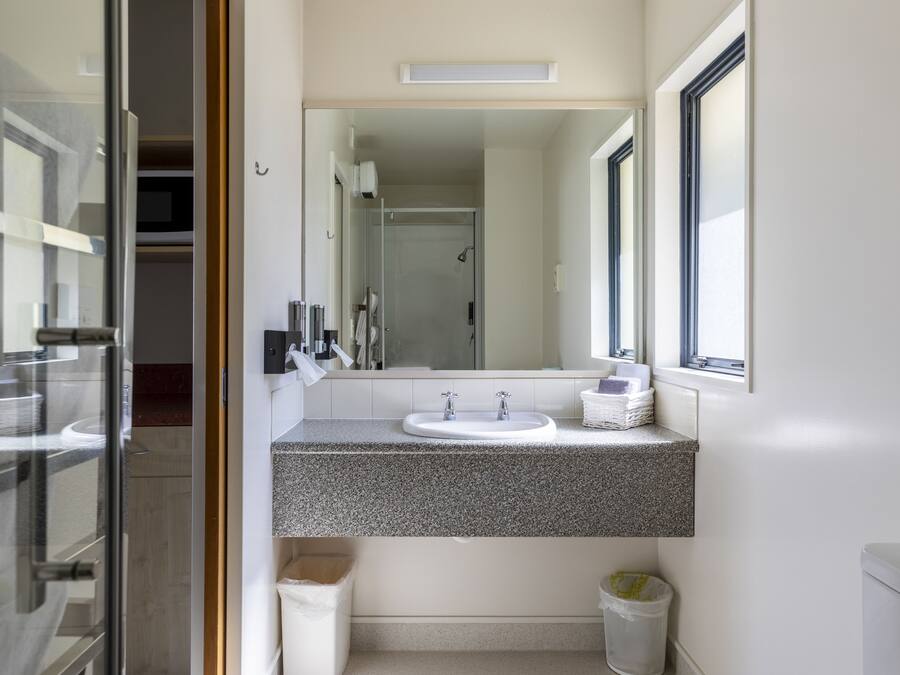 A modern bathroom with a granite countertop, a white sink, and a large mirror.