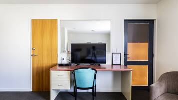 Ein Zimmer mit einem Holztisch, einem Stuhl, einem Fernseher und einer Tür.