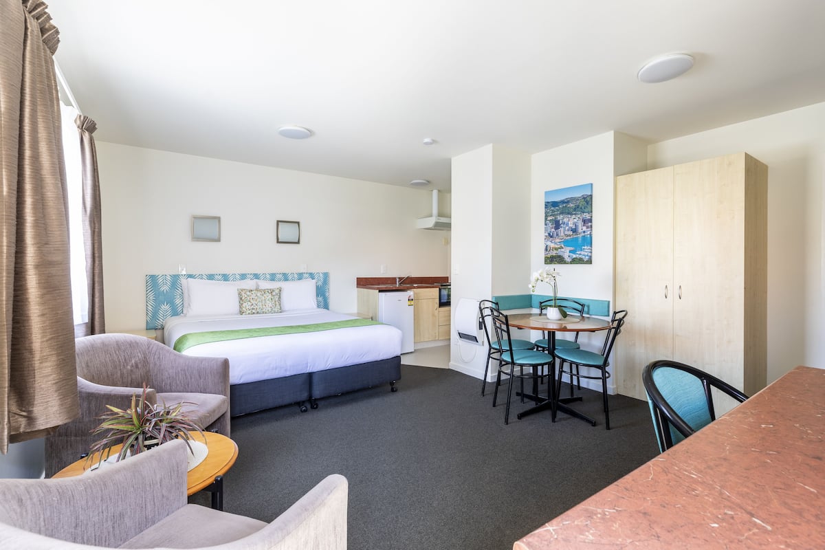 Ein Hotelzimmer mit Bett, Schreibtisch, Stuhl, Tisch und Kleiderschrank.
