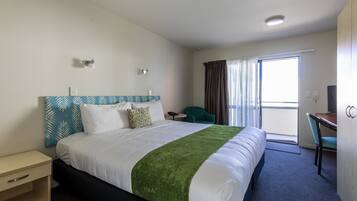 Ein Hotelzimmer mit Bett, Schreibtisch, Stuhl und Blick ins Freie.