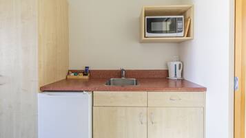 Cocina compacta con lavabo, microondas y hervidor.