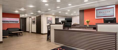 A reception area with a modern design, featuring a reception desk, seating area, and a wall-mounted sign.