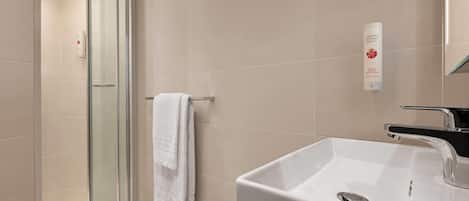 A modern bathroom with a glass shower enclosure, a white sink, and a towel rack.