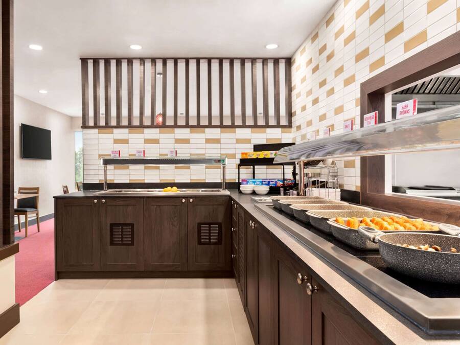 A modern kitchen with a central island, a buffet setup, and a TV mounted on the wall.