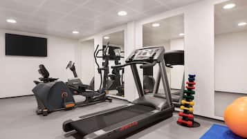 Et moderne fitnesscenter med løbebånd, crosstrainere og vægte.