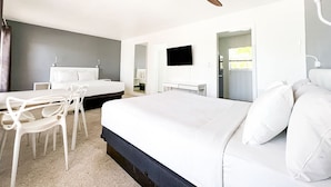 Une chambre d’hôtel moderne équipée d’un grand lit, d’un bureau, d’une chaise, d’un ventilateur de plafond et d’une télévision.