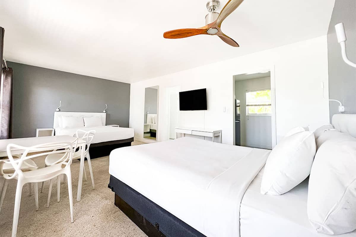 Une chambre d’hôtel moderne équipée d’un grand lit, d’un bureau, d’une chaise, d’un ventilateur de plafond et d’une télévision.