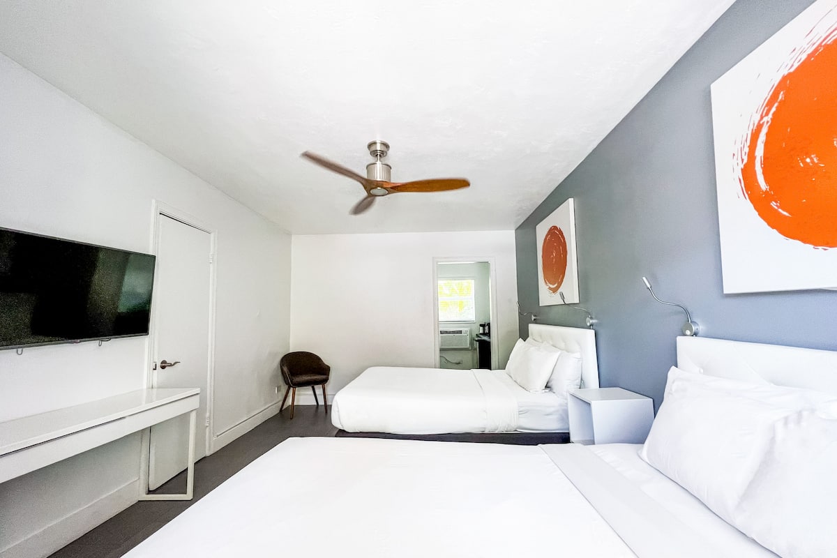 Une chambre d’hôtel moderne équipée d’un lit, d’un bureau, d’une chaise, d’un ventilateur de plafond et d’une télévision.