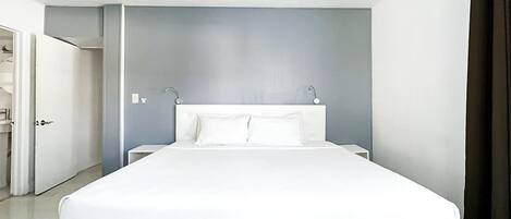 Una habitación de hotel con una cama grande, un ventilador de techo y una puerta que da a otra estancia.