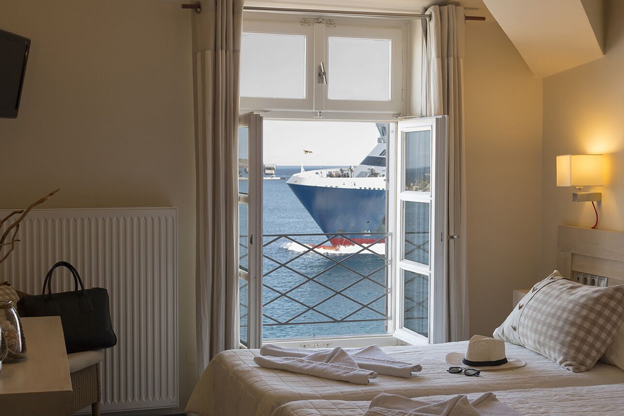 Habitación de hotel con un amplio ventanal que ofrece vistas de un barco.