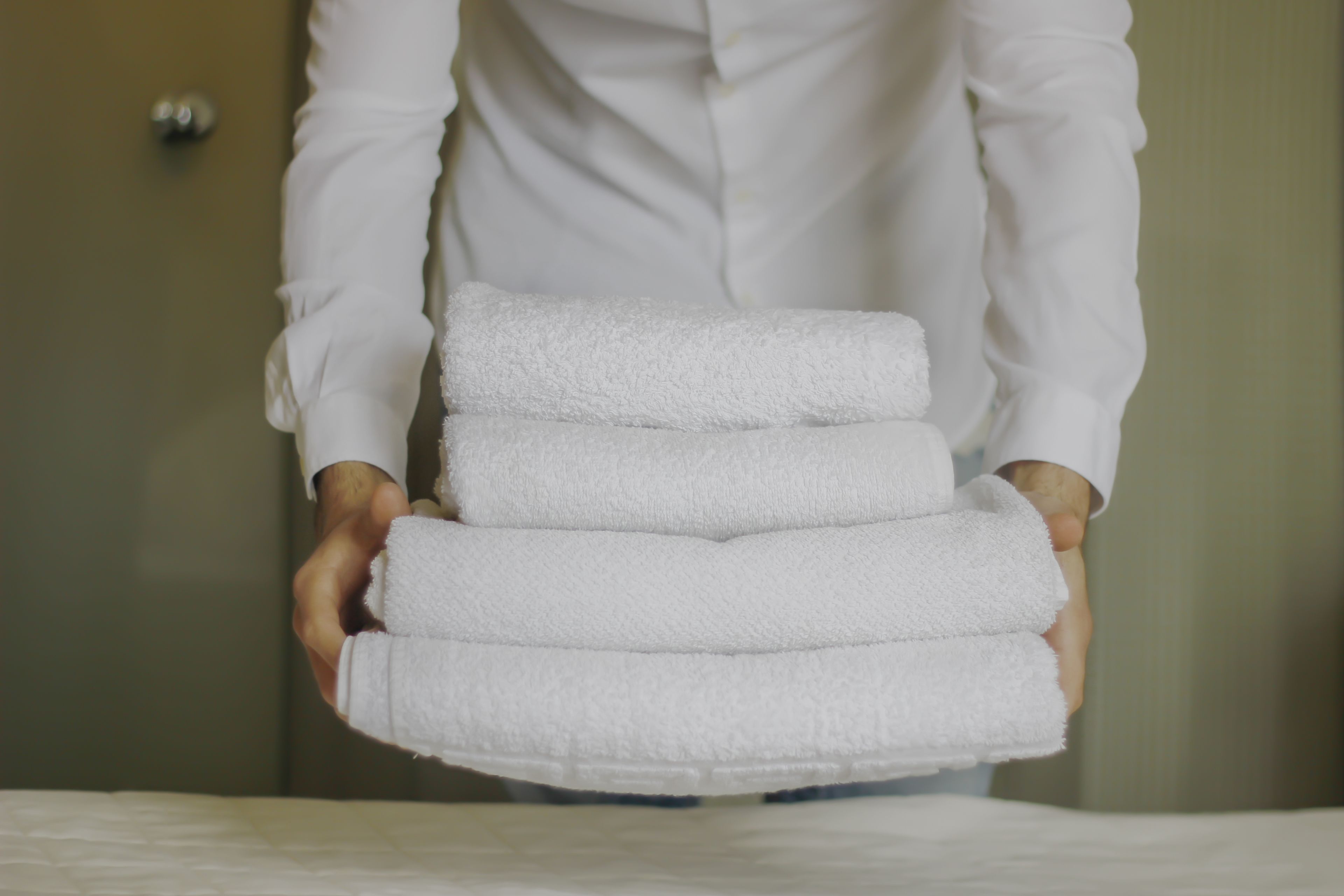 A person holding a stack of white towels.