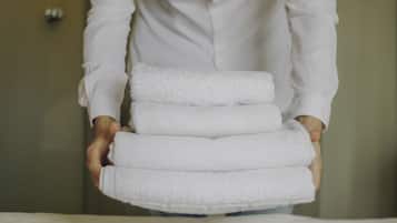 A person holding a stack of white towels.