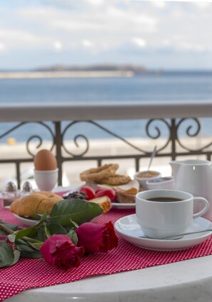 A table with breakfast items, a cup of coffee, and a view of the sea.