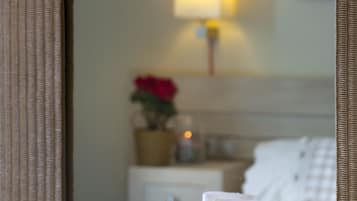 Una vela con conchas marinas y una rosa sobre una mesa, con un espejo que refleja una habitación.