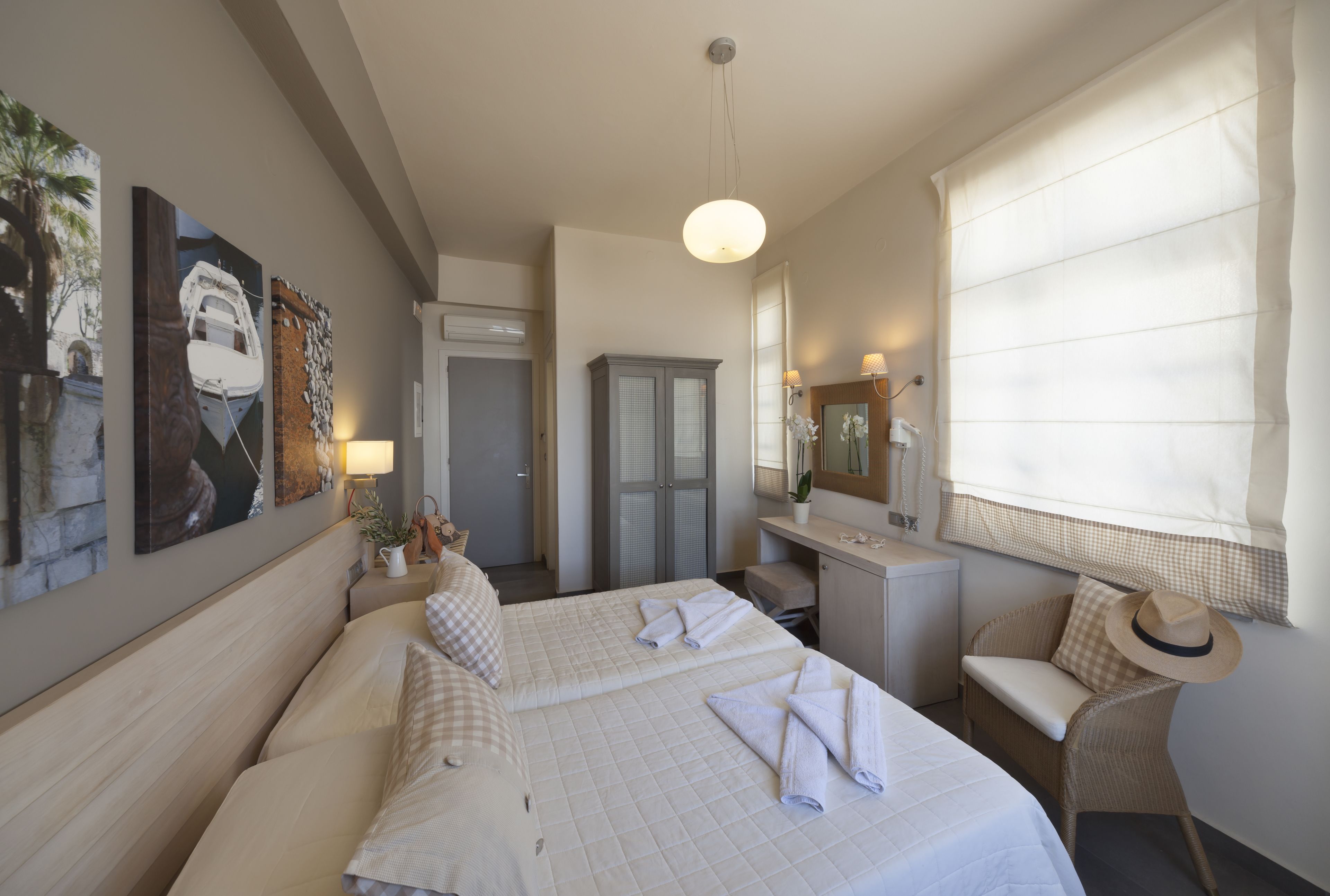 A hotel room with two beds, a desk, a chair, and a large window with curtains.
