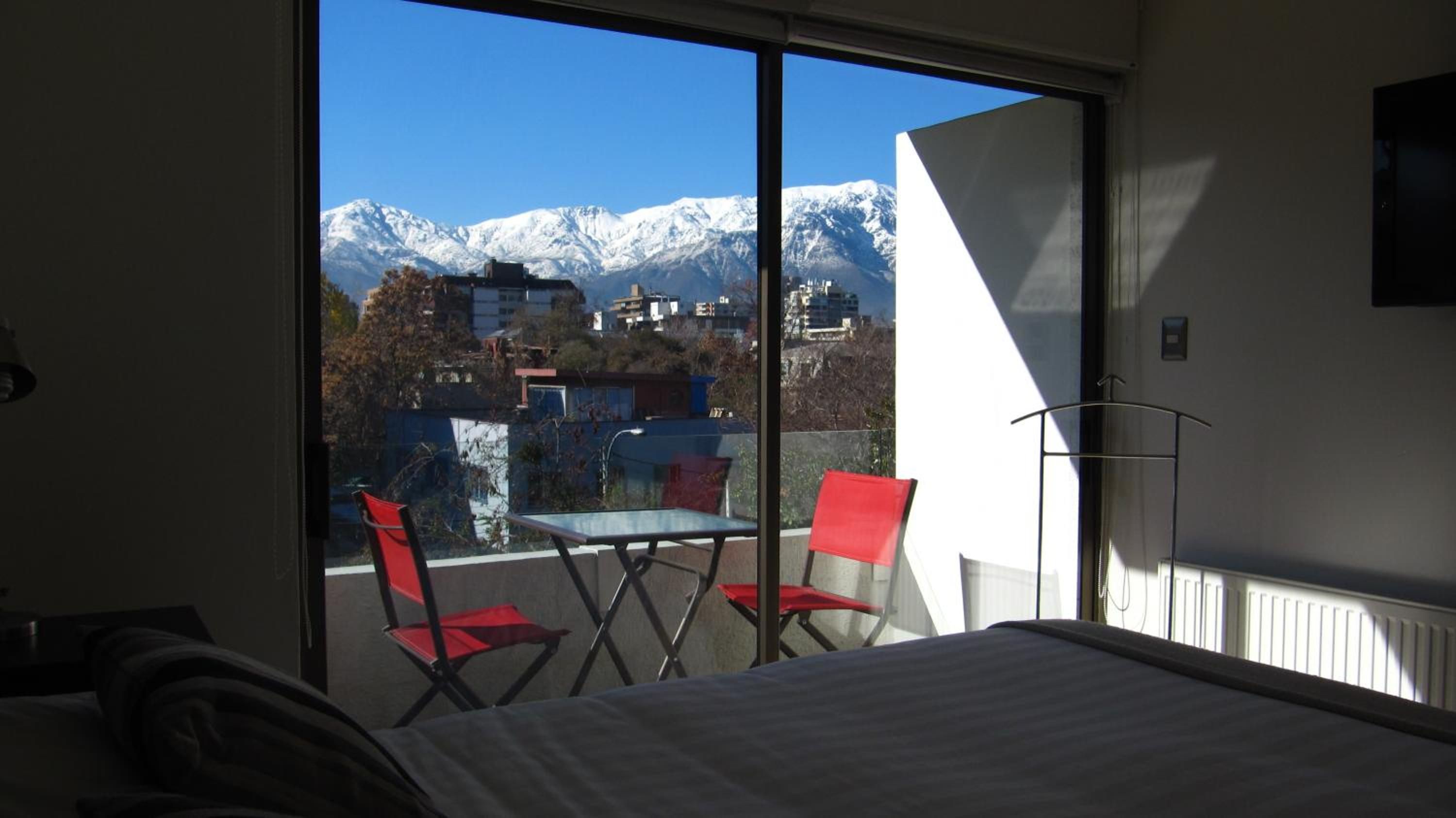 Habitación de hotel con un ventanal que ofrece vistas a montañas nevadas.