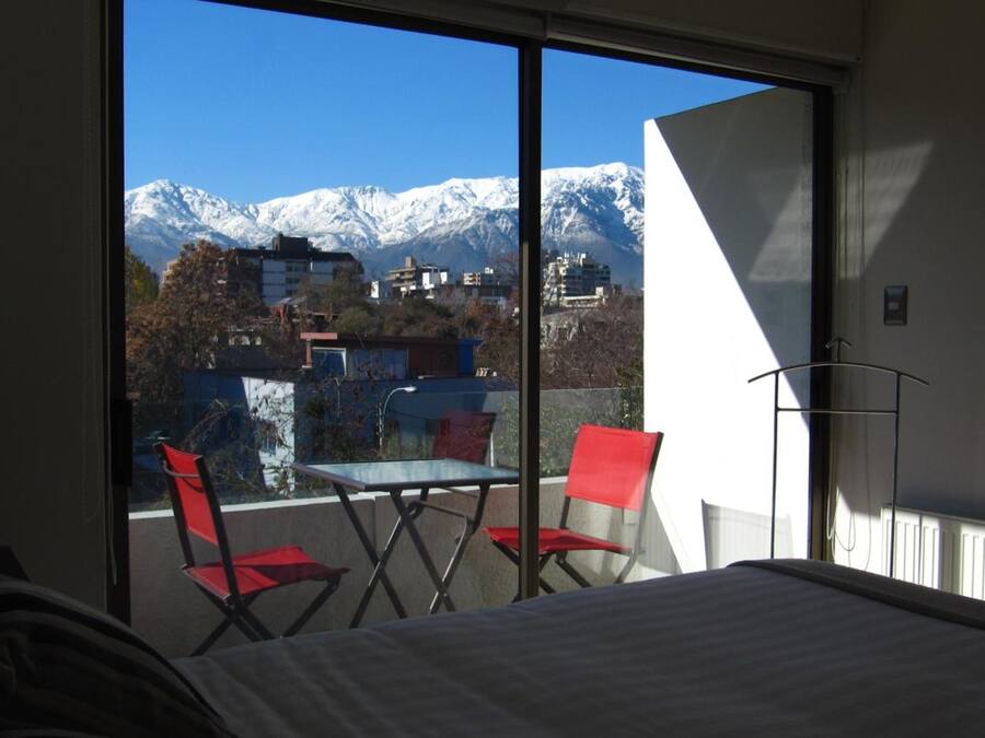 Habitación de hotel con un ventanal que ofrece vistas a montañas nevadas.