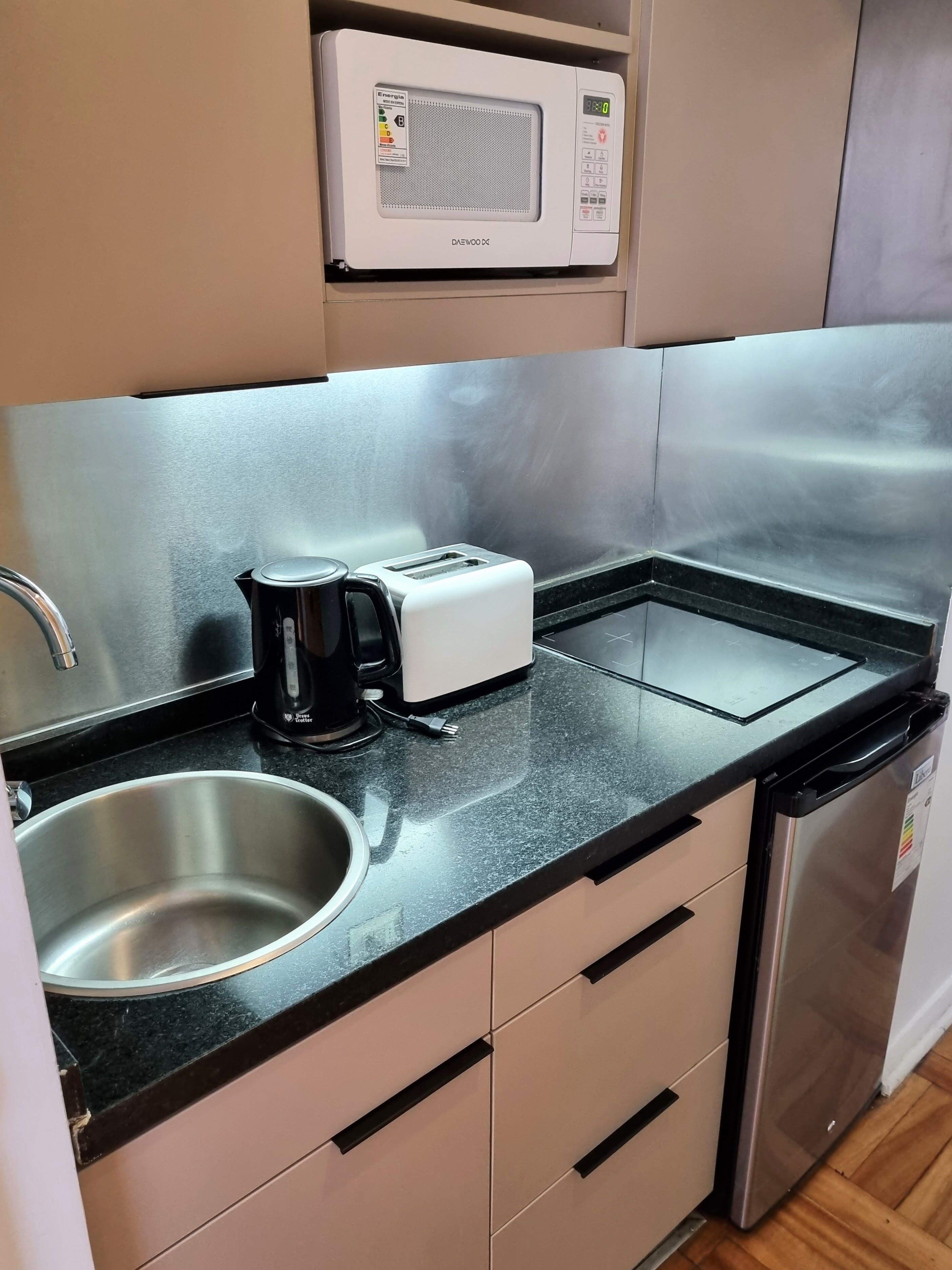 Une cuisine compacte équipée d’un four à micro-ondes, d’un grille-pain, d’une machine à café, d’un évier et d’un lave-vaisselle.
